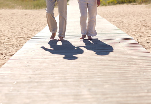 Close Up Of Senior Couple Walking On Summer Beach