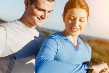 Runner woman with heart rate monitor running on beach