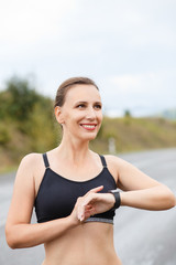 Young smiling fitness woman using her smart watch