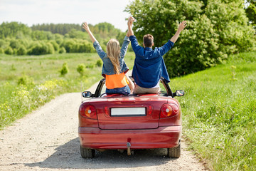 happy friends driving in cabriolet car at country