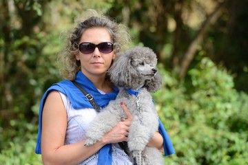 Portrait of a young woman with a poodle on hands