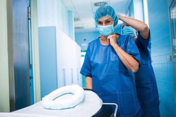 Nurse helping a surgeon in tying surgical mask