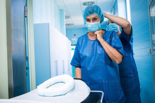 Nurse Helping A Surgeon In Tying Surgical Mask