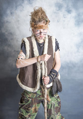 Portrait image of a teenage tribal warrior with a weapon. Taken on a blue background.