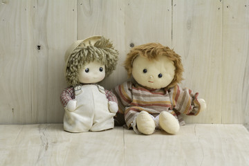 Stuffed two girls doll sitting on a wooden floor.