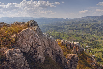 Fototapeta na wymiar Scenic alpine scenery with steep rocky slope and vast valley in Rucar-Bran pass, Transylvania region, Romania. Picturesque Romanian travel destinations.