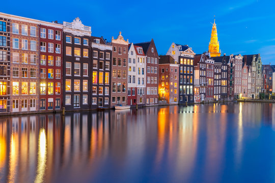 Amsterdam canal with Beautiful typical Dutch dancing houses and Oude Kerk church during twilight blue hour, Holland, Netherlands