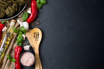 Vegetables, fresh herbs, hot spices and household goods stacked on a stone countertop. Photo...