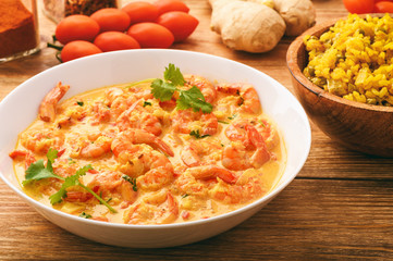 Indian cuisine - shrimps in ginger sauce and rice with curry and green pea.