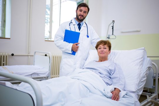 Smiling doctor and patient looking at camera in hospital