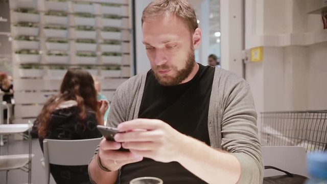 Man is being irritated. Man does not like his smartphone. Man holds a smartphone in his hand. Modern technology.