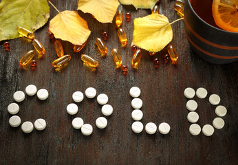 Concept of cold autumn - pills, leaves on dark wood