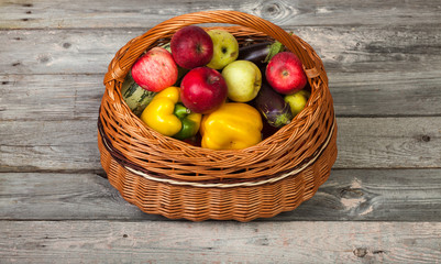 Obraz na płótnie Canvas Colorful vegetables and apples in basket on old wood table