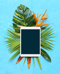 tropical plants with tablet on blue background