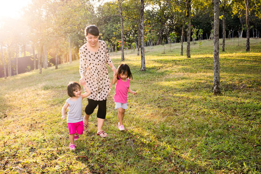 Asian Mom and Daughters Walking in the  Park