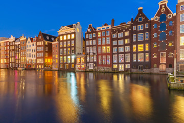 Naklejka premium Piękne typowe holenderskie domy taneczne nad kanałem Amsterdam Damrak w nocy, Holandia, Holandia.