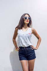 Girl brunette in summer in the park with resting in shorts and a white blouse on   background fashion lifestyle, gentle look. Sensual make-up, tanned skin  bright red lipstick. In sun glasses.