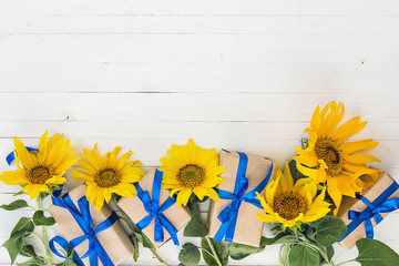 Background with a bouquet of yellow sunflowers and gift boxes wi