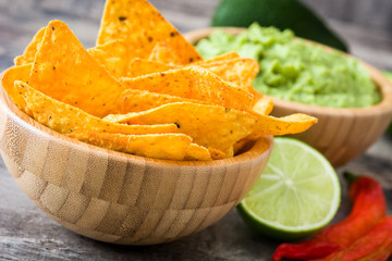 Nachos, guacamole and ingredients on wooden background


