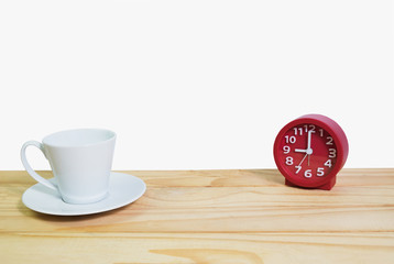 White cup of coffee  and red clock on wooden table with white background