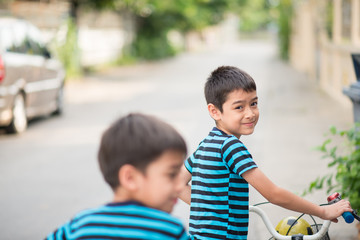 Little boy riding bicycle on the road around the house