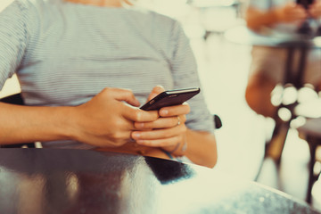 young cute woman using phone,sitting at a cafe holding a smartphone,answering texts,phone...