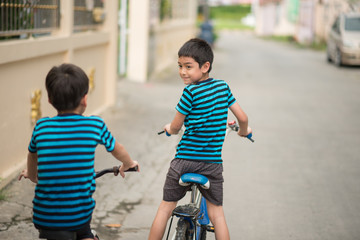Little boy riding bicycle on the road around the house