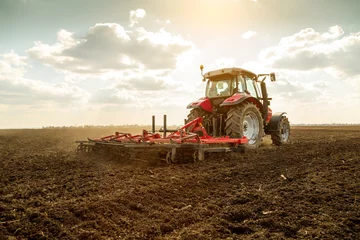 Photo sur Plexiglas Tracteur Agriculteur en tracteur préparant la terre avec cultivateur de lit de semence
