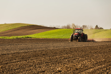 Obraz premium Farmer in tractor preparing land with seedbed cultivator