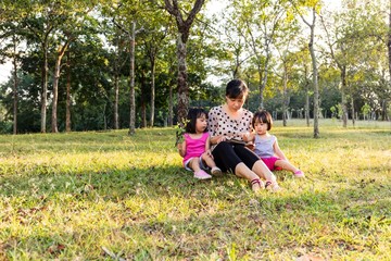 Asian Chinese Mother and Daughters Reading at Park