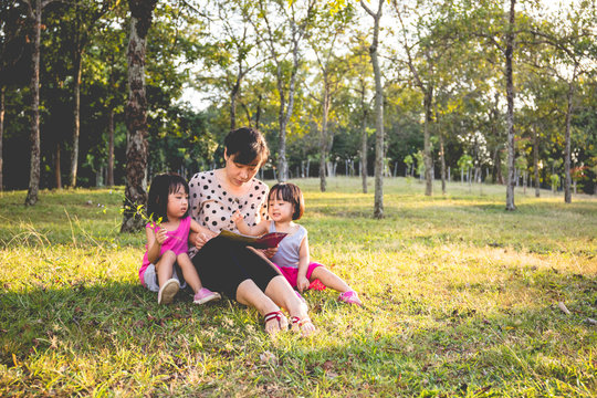 Asian Chinese Mother and Daughters Reading at Park