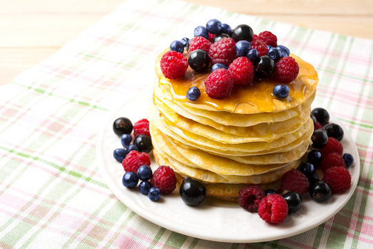 Stack of pancakes with honey, blueberry, raspberry and blackcurr