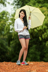 Asian woman listening to music with an umbrella