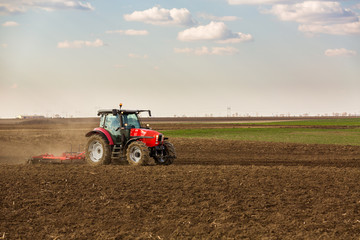 Obraz premium Farmer in tractor preparing land with seedbed cultivator