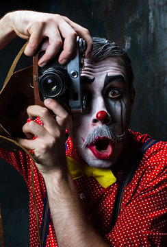 The Scary Clown And A Camera On Dack Background. Halloween Concept