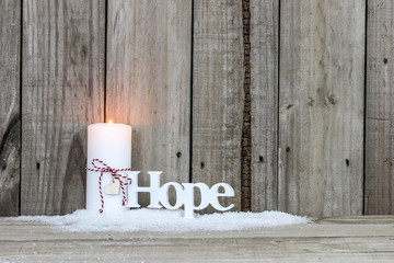 White holiday candle by the word Hope