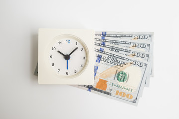Top view of square white alarm clock on dollar money cash