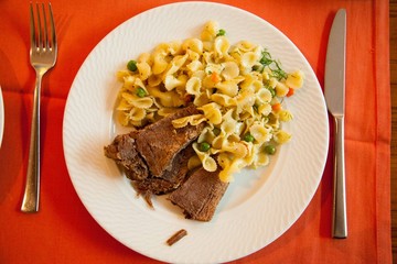 Roast lamb with noodles on the table