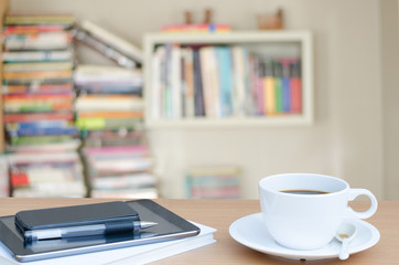 Cup of coffee on table in home library