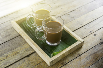 Old traditional Thai style coffee and hot chocolate or cocoa on the wooden table, sunshine and flare light blurred background, soft focus