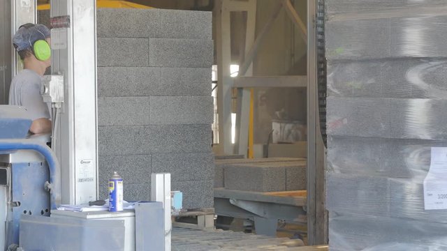 Operator works on the strapping machine at the concrete blocks factory