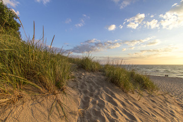 Warm Summer Breeze. Sunny afternoon day at the beach with a sand dune in the foreground and the beginnings of a sunset at the water's horizon. Hoffmaster State Park, Michigan.