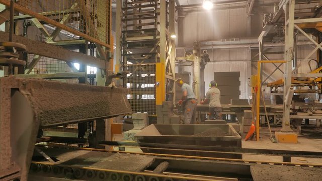 Operator and worker performing quality check on a concrete blocks factory