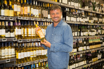 Man looking at bottle of wine in supermarket