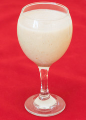 smoothies with milk, banana and oat flakes on a red background