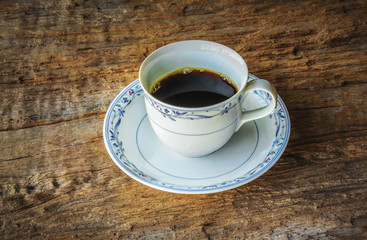 Coffee cup in gloomy light of the corner,on wood background. Refreshment after hours of work.
