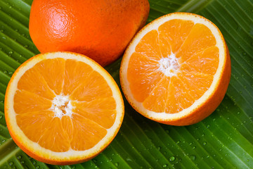 Fresh oranges cut in half on green banana leaf background