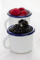 Fototapeta na wymiar blackberries in white cup on blue wooden background