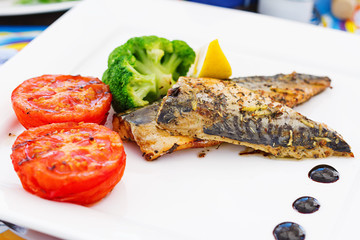 Mackerel fillets (fish) on a grill with vegetables