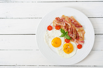 English breakfast - fried egg, tomatoes and bacon. Top view.